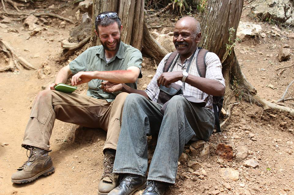 Andrew Zipkin working with a local collaborator, James Lenges, on Mt. Ng’iro, Kenya, to collect samples of ochre and iron ore (seen as pigment on Zipkin’s arm). (Photo courtesy of Andrew Zipkin.) 