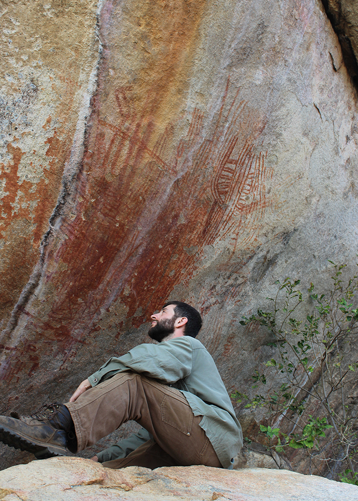 Andrew Zipkin examines ochre rock art at Mwanambavi Hill, Malawi, in 2016. (Photo courtesy of Andrew Zipkin.) 