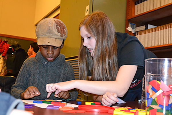 An Illinois math student works on a tile puzzle with a local youngster at the Math Carnival’s Tile Emporium station. (Photo by Elizabeth Innes.) 