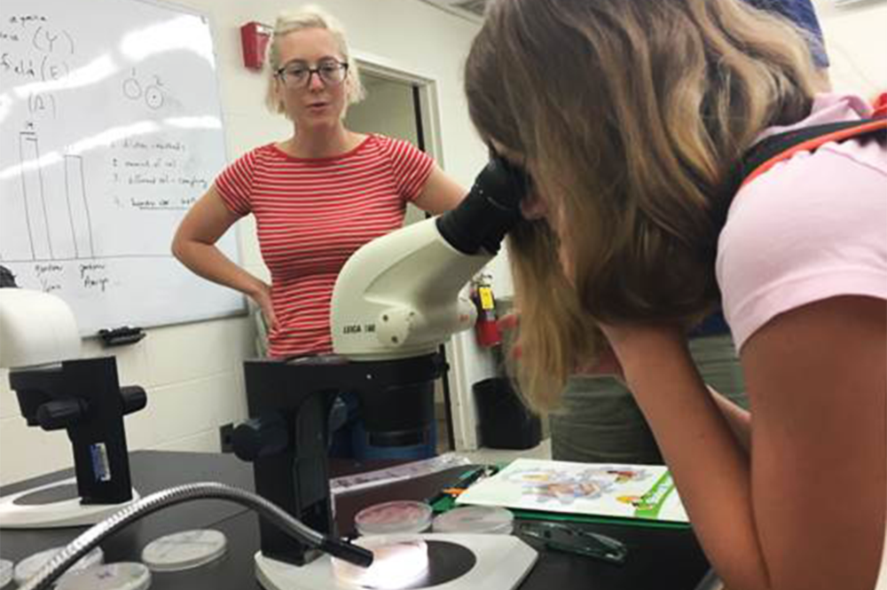 Katy Heath, left, professor of plant biology, helps a camper examine pond water at the Girls Explore Biology Camp. 
