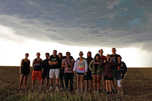 Students in a field in front of a storm