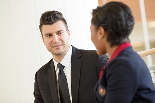 A man in a sut talks to a woman in a suit
