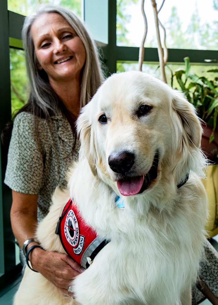 Joey Ramp, a senior in molecular and cellular biology, relies upon the support of her service dog, Sampson, to conduct research in a laboratory. (Photo by Jesse Wallace.) 